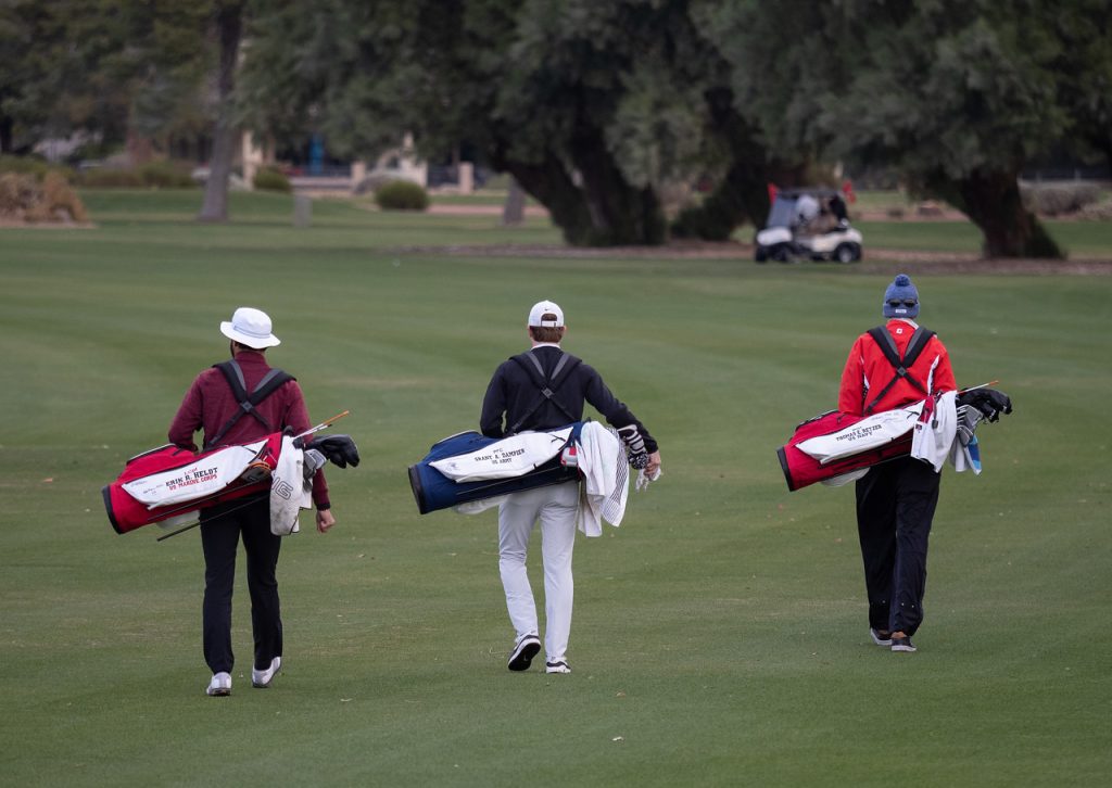 Compeitors walk down the fairway with their custom bags honoring fallen soldiers.